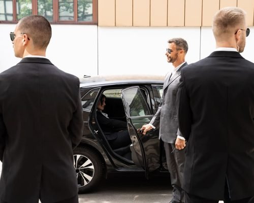 Professional chauffeur and security team beside a black SUV